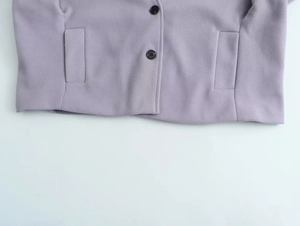 Gros plan du manteau en laine lavande avec boutons noirs et poches passepoilées