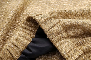 Macro shot of gold sequin tweed jacket featuring elastic waist and black lining detail