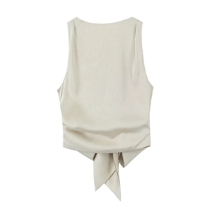 Flat lay of a beige satin backless top featuring a detailed bow-tie hem and silky texture
