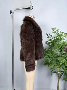 Détail de la texture d'un manteau en fausse fourrure marron foncé sur un mannequin beige