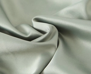 Close-up of sage green silk satin fabric showing elegant drapes and smooth texture