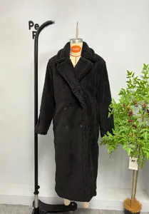 Gros plan sur la texture en peluche noire et les boutons croisés du long manteau d'hiver
