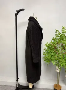 Profil latéral d'un long manteau teddy noir avec de larges revers et une texture polaire