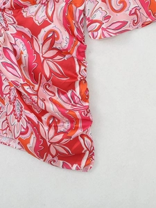 Gros plan sur l'imprimé floral tropical et le détail froncé d'une robe courte à col en V