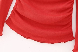 Detail of red off-shoulder cotton top featuring side ruffles and pleated knit texture