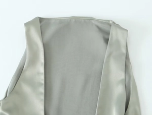 Detail of V-neckline on light sage green satin vest with smooth silk texture