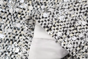Macro shot of black and white tweed fabric with silver sequins and white lining