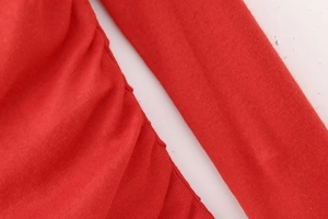 Detailed close-up of vibrant red knit fabric featuring vertical texture and side ruching