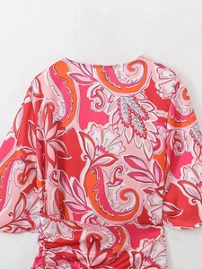 Détail de robe à col en V avec imprimé paisley rose et fronces latérales du tissu