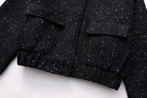 Detail of black tweed jacket featuring subtle silver sequins and a flap pocket design