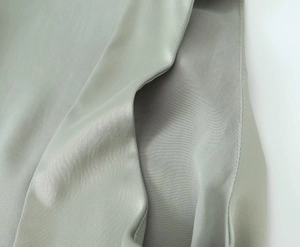 Close-up of sage green satin fabric showing smooth texture and fine stitching detail