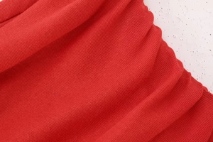 Detailed macro view of the bright red ribbed knit cotton fabric texture and soft pleats