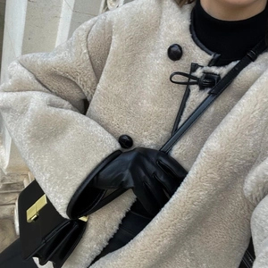 Manteau en fausse fourrure beige avec bordure en cuir noir et boutons ronds en gros plan