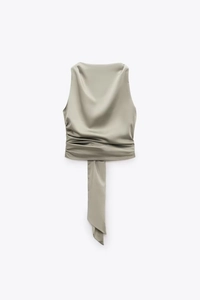 Detail of sage green satin top featuring elegant cowl neck and flowing silk ribbon