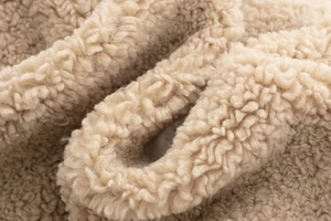 Gros plan détaillé du tissu polaire sherpa beige montrant la texture bouclée