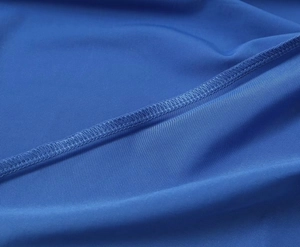 Primer plano detallado de la costura overlock precisa en la tela textil azulada