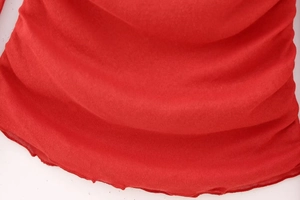 Close-up of red ribbed knit fabric featuring a decorative lettuce edge hem and fine texture