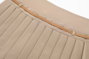 Dettaglio di gonna a pieghe kaki con sottile cintura in pelle marrone e pieghe definite