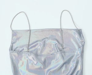 Detalle de tela holográfica plateada y finos tirantes de cadena de strass en el vestido