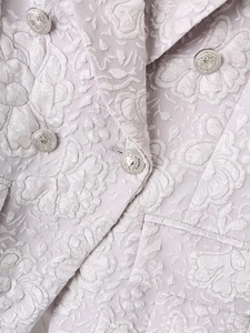 Detailed macro view of lavender floral jacquard fabric and silver metal button on blazer