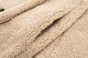 Détail macro du tissu polaire sherpa beige et couture de la poche sur le manteau long
