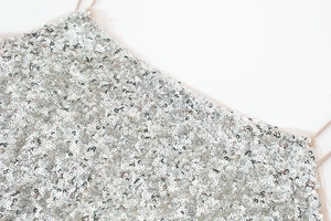 Close-up of sparkling silver sequins and delicate pink mesh trim on an elegant dress