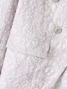 Detailed view of light purple textured jacquard fabric and silver embossed metal button