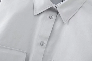 Détail d'une chemise grise montrant le col polo et les boutons en résine durable