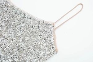 Detailed close-up of silver sequins on a slim strap dress with mesh edging detail
