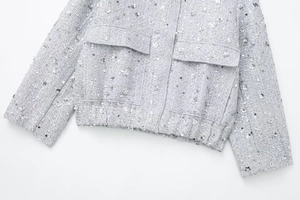 Detail of grey tweed jacket featuring shimmering silver sequins and flap pockets