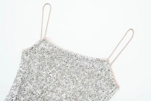 Detail of silver sequined camisole top with thin straps and sheer mesh trim edges