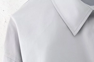 Détail du col polo gris clair et coutures précises sur le tissu en sergé de la chemise