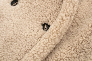 Gros plan sur le tissu moumoute beige et les boutons foncés à texture bois