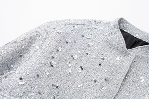 Macro shot of silver sequined tweed fabric on a women's jacket with silk lining detail