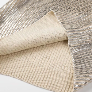 Detail of silver metallic knit fabric with sequins and a soft beige knitted lining