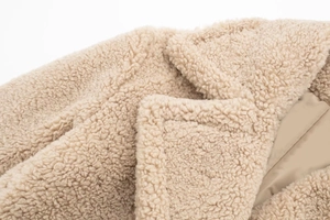 Détail du col d'un manteau en polaire beige montrant la texture épaisse du molleton bouclé