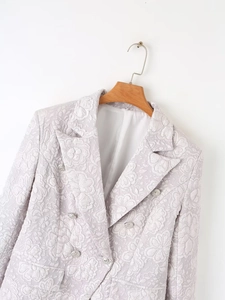 Detailed close-up of light purple textured blazer with silver buttons and floral jacquard