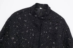 Detail of black tweed jacket featuring stand collar and shimmering sequin floral patterns