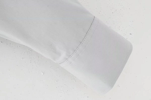Détail du poignet d'une chemise gris clair montrant le tissage sergé et les coutures
