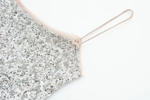 Detail of silver sequined dress featuring soft pink faux fur trim and thin straps
