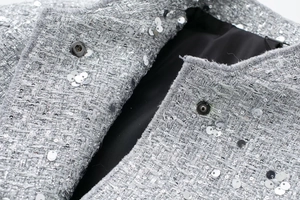 Detailed macro of silver sequin tweed jacket with sparkling fiber and metallic fasteners
