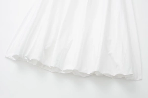Détail de l'ourlet d'une robe midi blanche avec plis élégants et coton de qualité