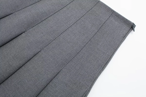 Macro detail of grey pleated skirt showing smooth hidden zipper and woven fabric texture