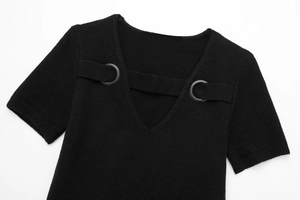 Detailed close-up of a black knit dress featuring a deep V-neck and decorative buckle straps