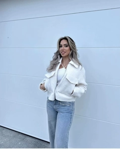 Close-up of white fleece cropped jacket featuring large collar and metal zipper pockets