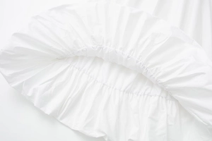 Détail de la jupe midi blanche avec des plis raffinés et une texture en coton doux