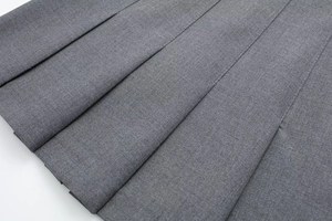 Macro detail of high-quality grey pleated skirt fabric showing clean diagonal pleat lines