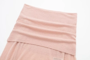 Close-up of light pink knit fabric showing the detailed 100% cashmere texture and weave
