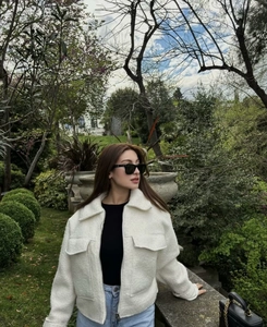 Detailed close-up of white fleece short jacket with large lapels and flap chest pockets