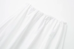 Détail de la jupe midi blanche avec taille élastiquée et texture de tissu tissé de qualité